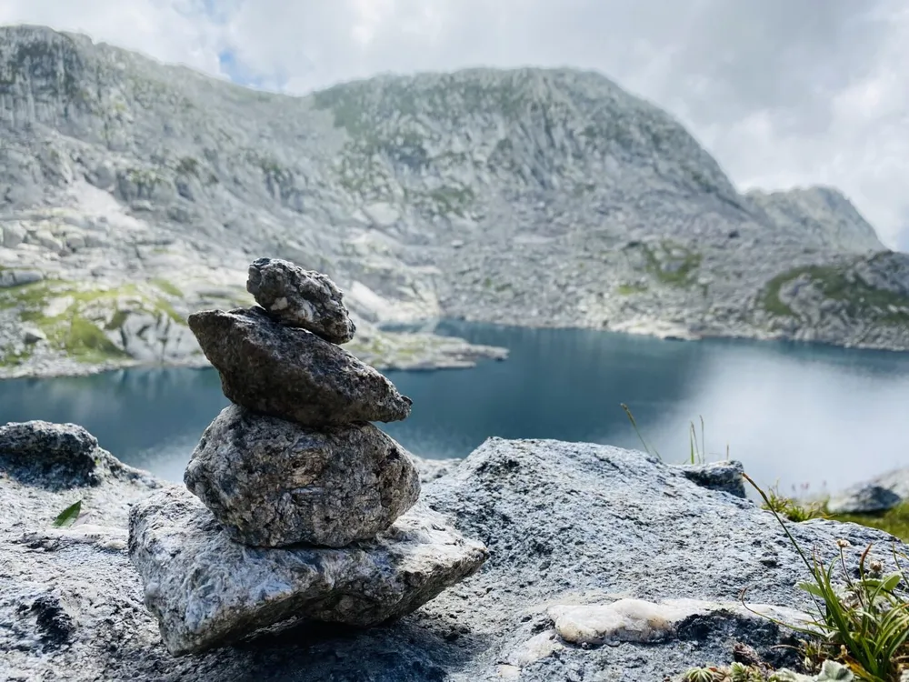 A stone cairn above a quiet alpine lake in the Dhauladhar